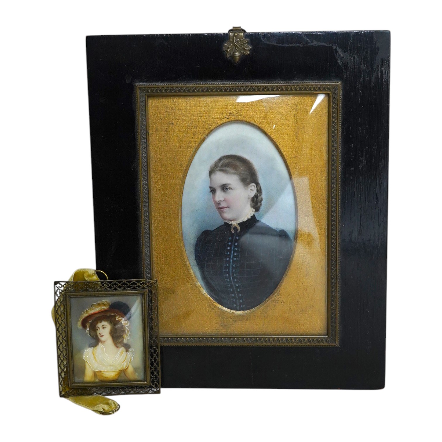 Two 19th century portrait miniatures on simulated ivory and card, comprising portrait of a Regency lady and portrait of a late Victorian lady in mourning, largest overall 24 x 19cm. Condition - fair